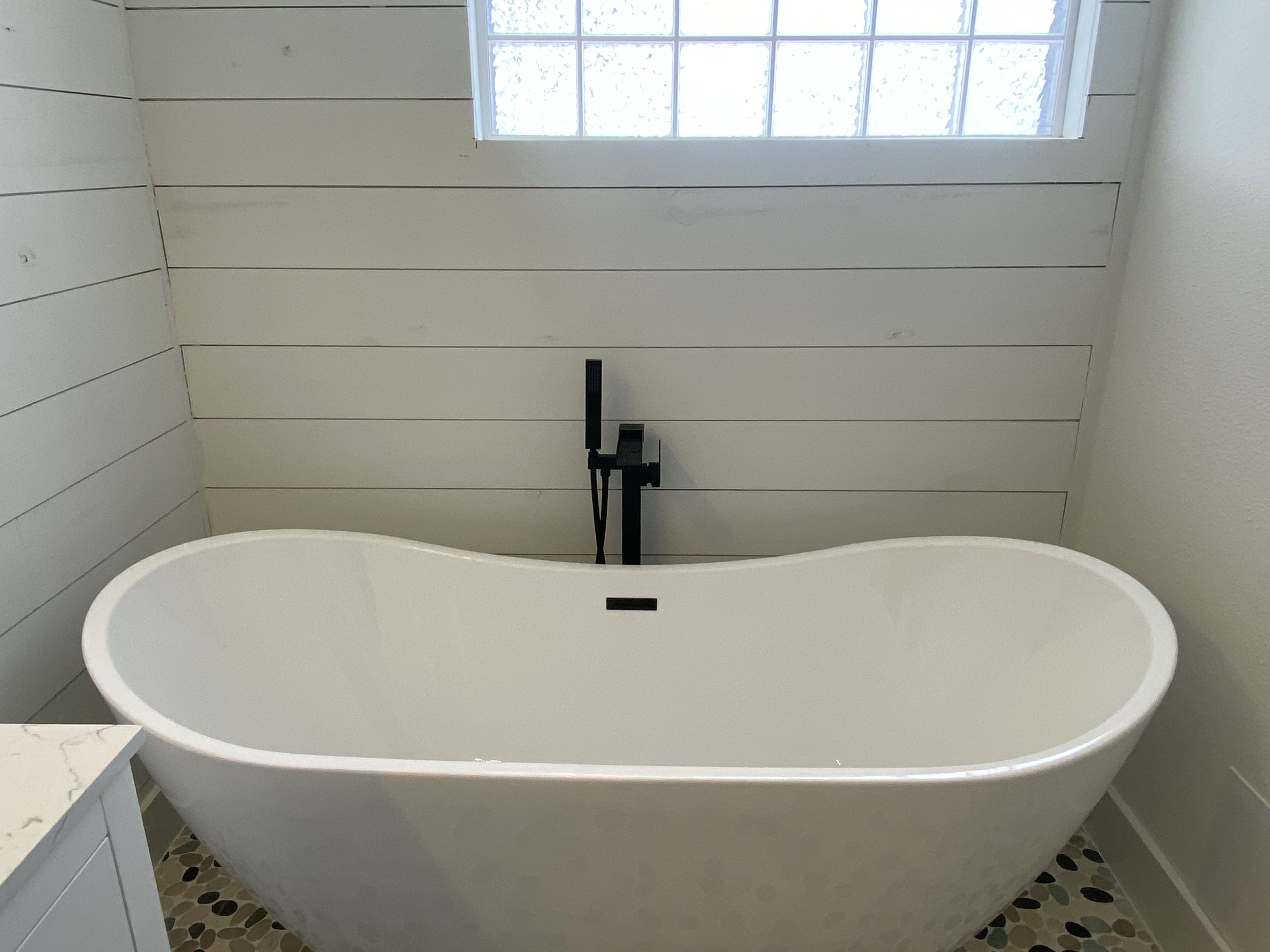 Close view of completed freestanding bathtub and black tub filler installation