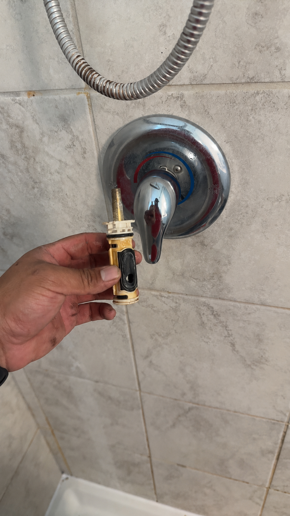 Plumber holding a removed shower valve cartridge during shower repair